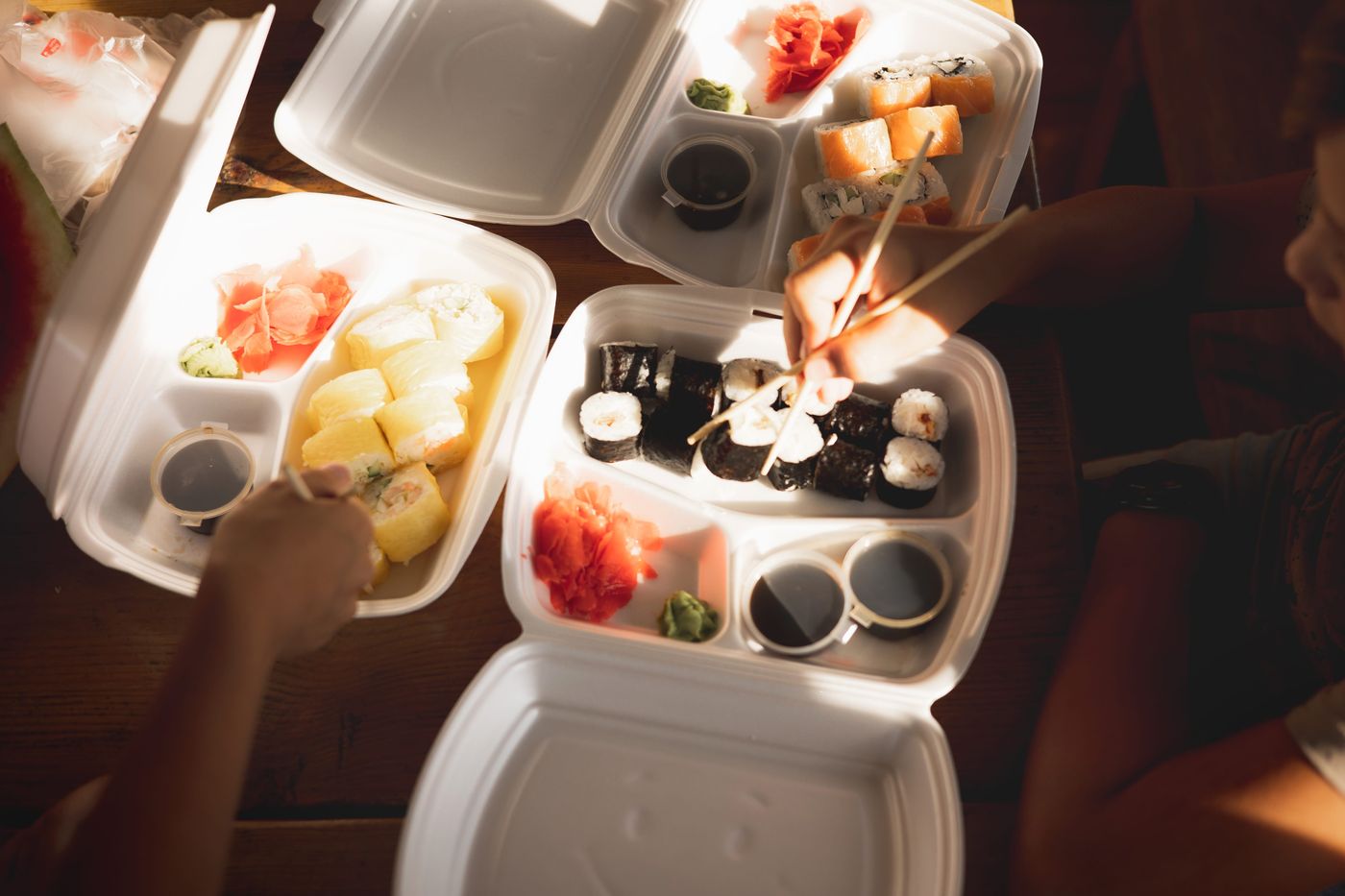 Sushi rolls served in white hinged take-out containers