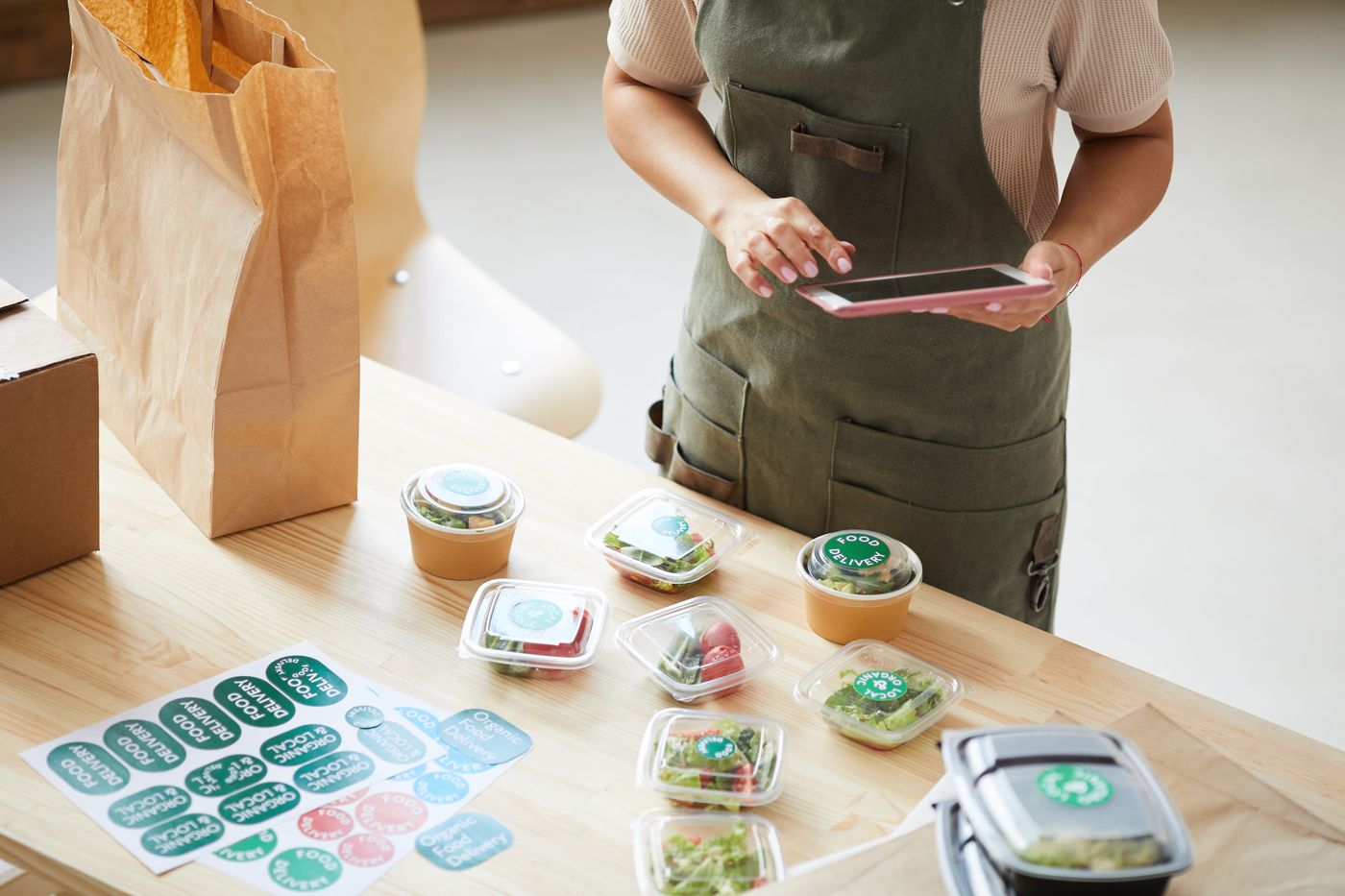 Take-out salad containers and kraft bag being prepared for delivery